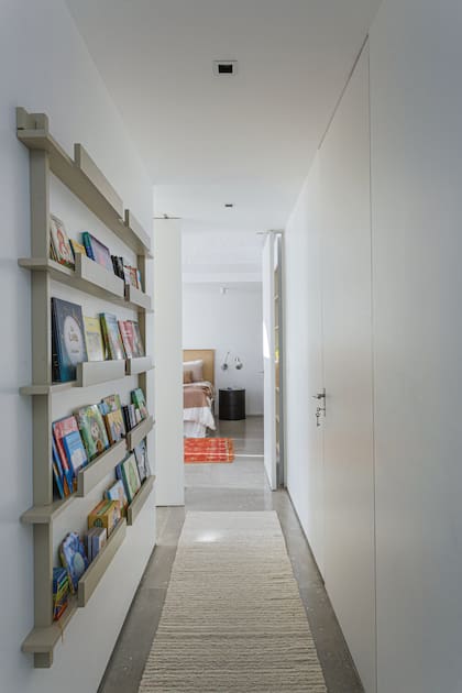 Con una biblioteca chata en el pasillo de la casa de una arquitecta, se ordenan todos los libros infantiles de sus hijos casi sin ocupar volumen.