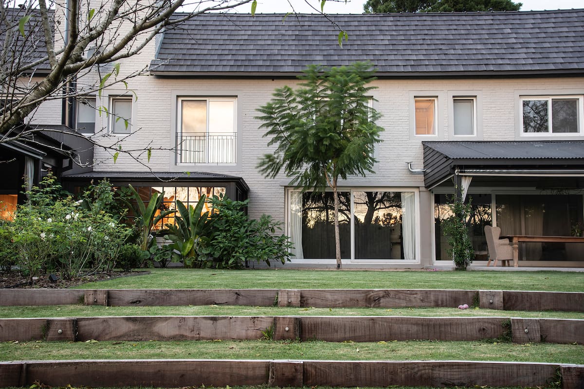 Escalones de césped salvan el desnivel entre la casa y el resto del jardín que mira hacia el golf.