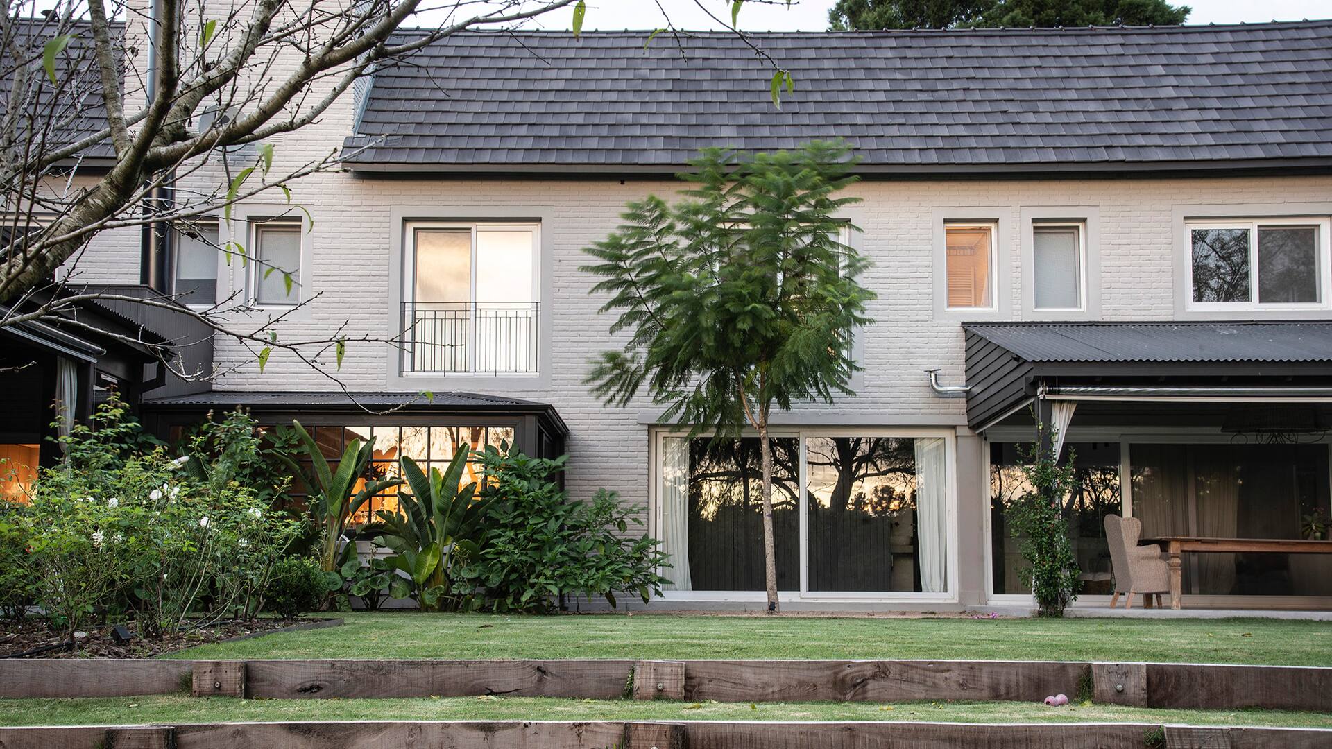 Escalones de césped salvan el desnivel entre la casa y el resto del jardín que mira hacia el golf.