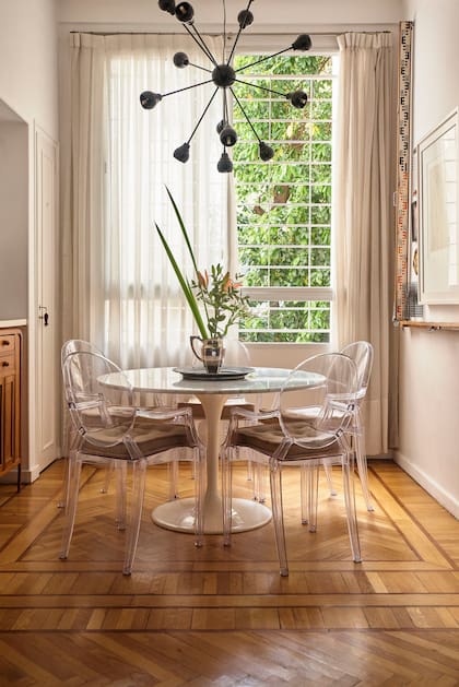 Conectado con el living y con vista al patio arbolado, el comedor con mesa ‘Tulip’, sillas ‘Louis Ghost’ de Philippe Starck y lámpara estilo Sputnik es el lugar preferido de Mario para almorzar