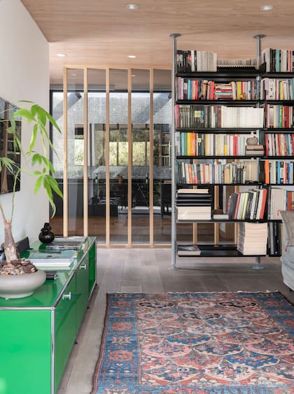 Consola verde ‘Haller’ (USM). Biblioteca diseñada por Dieter Rams (Vitsœ), un clásico. Por detrás del antebaño, patio interno revestido en venecitas negras.