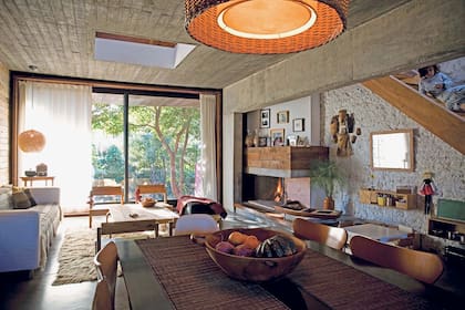 Contra la ventana, sillón de Ikea con manta del norte argentino y sillas materas hechas con madera reciclada. El revestimiento de la chimenea es parte del reciclaje del techo original.
