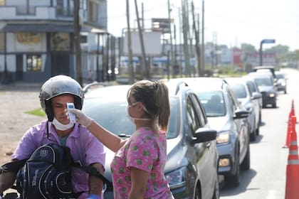 Una voluntaria mide la temperatura de un motociclista en el control de circulación de Ezeiza (ruta 205 y De Vedia). Una de las medidas de restricción por la pandemia de coronavirus