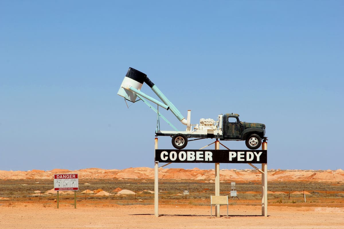 COOBER PEDY, AUSTRALIA - December 1, 2015. Sign of Coober Pedy with a digging machine on truck in the mining area. And danger sign. This mining town in the Outback is famous because of the opal mines.