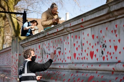 Corazones rojos están pintados en la pared del terraplén en el lado sur del río Támesis en memoria de aquellos que perdieron la vida por el Covid-19 en Londres el 29 de marzo de 2021