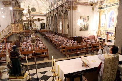 El sacerdote Raúl García oficia una misa de Semana Santa frente a fotos de los fieles de la iglesia de Nuestra Señora de la Paz, en el pueblo de Villar del Arzobispo, cerca de Valencia, España
