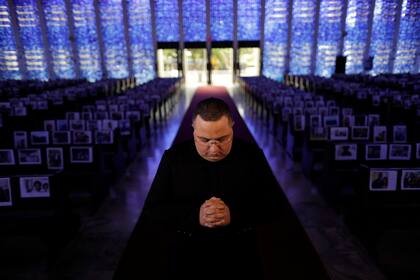 El sacerdote católico Jonathan Costa reza entre fotos de fieles en la iglesia Santuario Dom Bosco, en medio del brote de la enfermedad por coronavirus (COVID-19), en Brasilia, Brasil