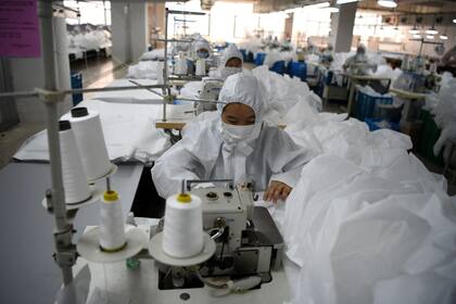 Trabajadores cosen trajes protectores para usar contra el coronavirus