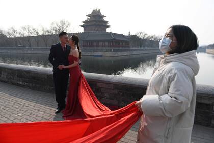 Una pareja se toma fotografías junto a la Ciudad Prohibida