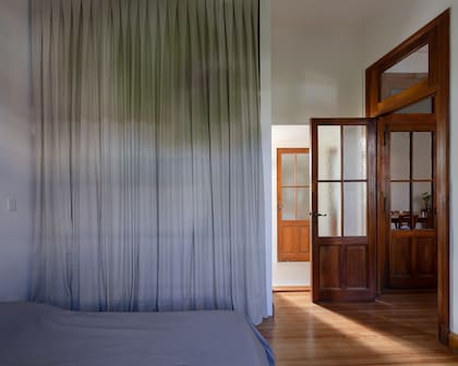 Cortinas de tussor (confección Ethia Home) para cerrar el placard de la habitación. Al fondo, cruzando el pasillo gris, está el baño. A la derecha, la salida al espacio social y la puerta del toilette.