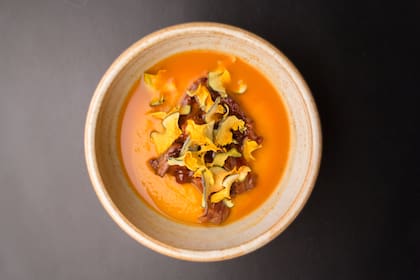 Crema de zanahoria, chivo a la llama y calabaza seca.