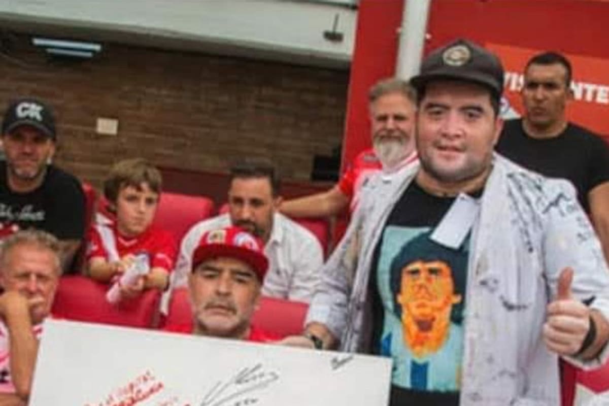 Cristian Landi, con Diego Maradona, mostrando la pintura que hizo del 10