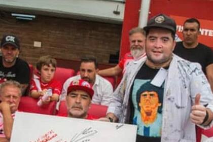 Cristian Landi, con Diego Maradona, mostrando la pintura que hizo del 10
