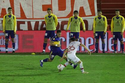 Cristian Pavón encara a Ezequiel Bonifacio y acapara la atención de los suplentes xeneizes.