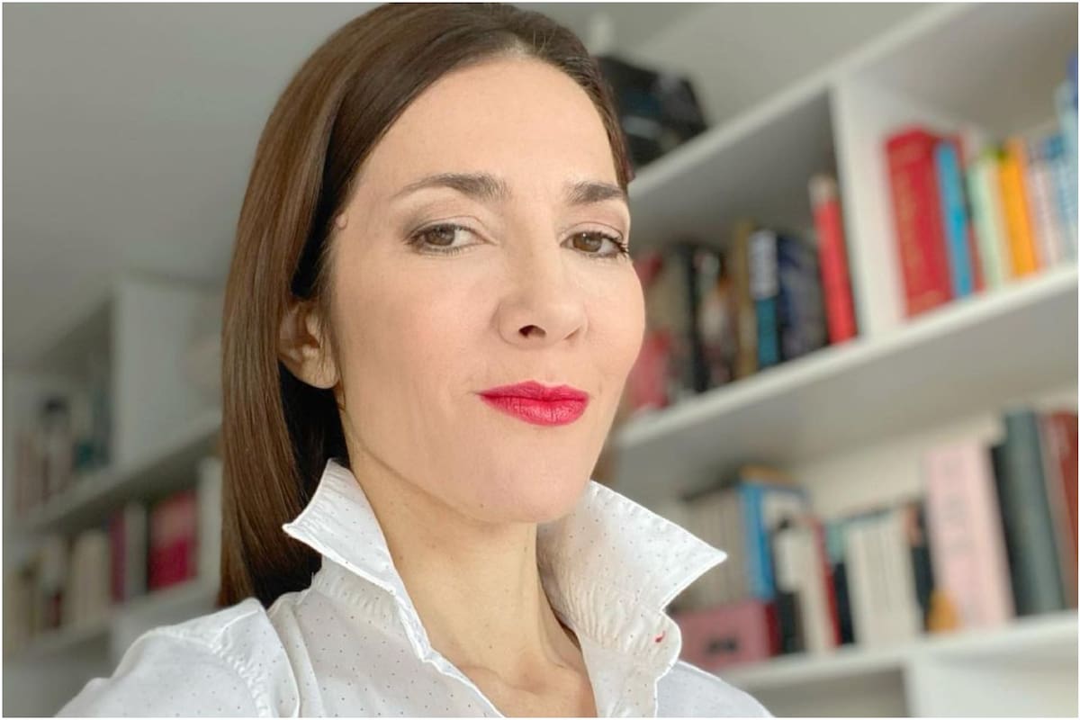 Cristina Pérez y la enorme biblioteca de su departamento de fondo