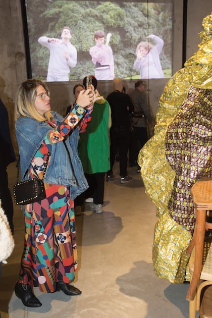 Cristina Tweety Dodero, impactada con Desvelo, una de las obras que Ama realizó con envoltorios de caramelos. Detrás, sobre la pared, se proyecta Temporada de eclipses, un video digital hecho con cuatro performers que realizaron secuencias repetibles basándose en los colores. La artista tiene varios trabajos en videoarte.