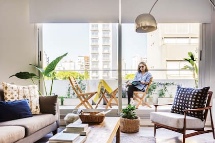 El piso flotante se reemplazó por porcelanato ‘Legni Ego’ (ILVA). En living, silla escandinava y sillón de dos cuerpos tapizados con géneros de De Levie y lámpara ‘Arco’ que Paula trajo de la casa de sus padres,
