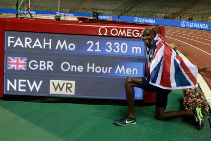 Cubierto con la bandera británica, Mo Farah posa para una foto junto a un tablero que indica que batió un récord mundial durante la justa One Hour Men en Bruselas el 4 de septiembre del 2020. (AP Photo/Virginia Mayo, File)