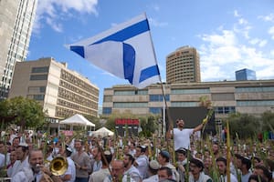 Cubiertos con chales de oración, hombres bailan y sostienen los cuatro símbolos de la festividad judía de Sucot, en la Plaza de los Rehenes.