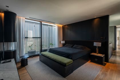Cubre sommier en paraíso de poro abierto negro, con banco de guardado integrado al pie de cama y colchoneta tapizada en terciopelo verde. Respaldo de cama con zócalo de paraíso de poro abierto y panel entelado en lino negro.