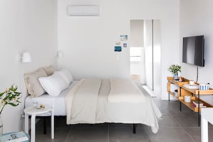 Cubreedredón de tusor rayado lavable (Pez Punto). La repisa en módulos apilables (Tortuga) puede llegar a usarse como biblioteca para dividir la cama del living de manera útil y liviana.
