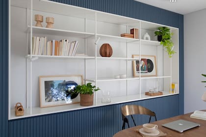 Cubriendo toda la pared, mueble varillado laqueado en azul ‘Into The Stratosphere 0627’ (Sinteplast) con estantería metálica blanca, diseñado y ejecutado a medida por el equipo de interiorismo. Objetos (Philippa Deco Boutique).