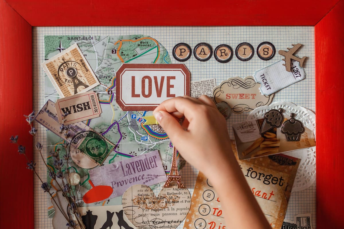 Cute girl dreaming about travel to France and creating mood board with sheets of paper, pictures, words, positive thinking and dreams map, indoor lifestyle