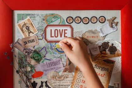 Cute girl dreaming about travel to France and creating mood board with sheets of paper, pictures, words, positive thinking and dreams map, indoor lifestyle