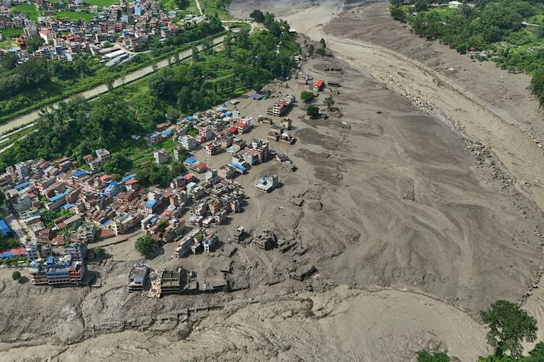 Damaged houses stand precariously near the swollen, debris-choked banks of the Trishuli River after flash floods in Nepal's Nuwakot district on Wednesday, Aug. 26, 2026. (AP Photo/Niranjan Shrestha)