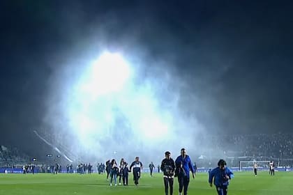 De fondo, los gases lacrimógenos; en primer plano, hinchas de Gimnasia intentan abandonar la cancha del Lobo