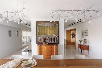 De inspiración vegetal, decenas de led componen la delicada lámpara ‘Heracleum II Suspended’, creada por Bertjan Pot para la firma holandesa Moooi. La vista hacia la entrada revela la cara más clásica de la ambientación, con muebles franceses heredados y un cuadro de Juan Ranieri