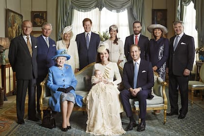 De izq. a der.: el príncipe Felipe de Edimburgo, Carlos de Inglaterra, Camilla, el príncipe Harry, Pippa, James, Carole y Michael Middleton. Abajo, la reina Isabel II, Kate con el bebe en brazos, y Gu