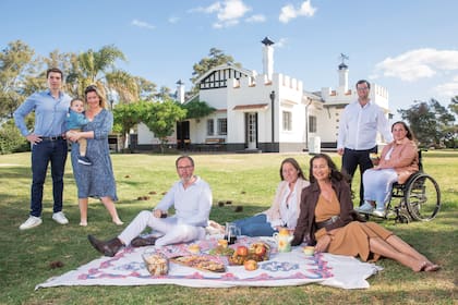 De izquierda a derecha: Delfina con Leo, su marido, y su hijo Bautista; Walter; Paulina; Andrea; Luciano y Agustina, en el parque de la estancia “La Familia”. Compraron el campo en 2010 y ampliaron el casco, que había sido construido en la década del 40.