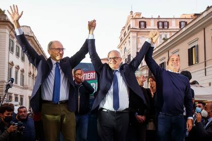 De izquierda a derecha, el líder del Partido Democrático, Enrico Letta; el alcalde electo de Roma, Roberto Gualtieri; y el presidente de la región de Lazio, Nicola Zingaretti, celebran el lunes 18 de octubre de 2021, en una plaza de Roma. (Roberto Monaldo/LaPresse via AP)