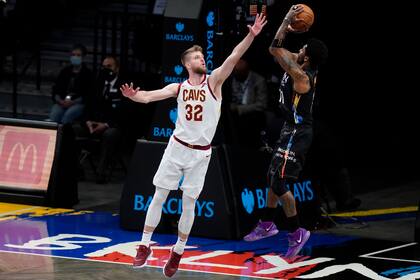 Dean Wade, izquierda, de los Cavaliers de Cleveland, intenta bloquear un tiro de Kyrie Irving, de los Nets de Brooklyn, en duelo de la NBA el domingo 16 de mayo de 2021, en Nueva York. (AP Foto/Frank Franklin II)