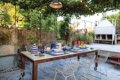 Pérgola (Marcelo Castelar), mesa de hierro y Silestone (Alberto Di Marco) con vajilla de cerámica artesanal (Candela González Arzac), sillas ‘Bertoia’ (Manifesto Design Store) y lámpara galponera (Electricidad Ramallo).