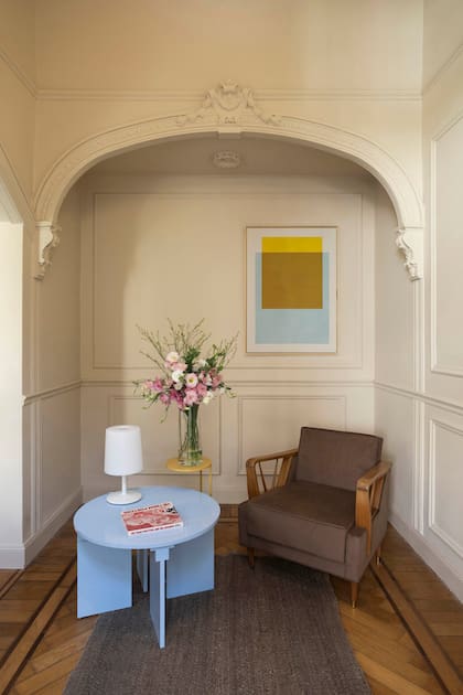 Debajo del arco armaron un antedormitorio con un sillón Mid Century de haya y tapizado color café, y una mesa ‘Afra’ celeste con lámpara (Intervista). Alfombra de lana ‘Monte’ (Elementos Argentinos). Obra (Pared).