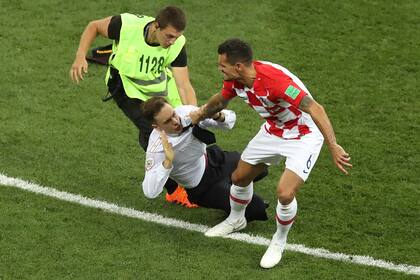 Dejan Lovren, defensor de Croacia, tomando a uno de los manifestantes para sacarlo del campo de juego.