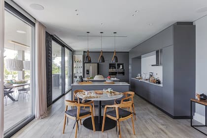 Del otro lado del desayunador, el comedor diario con mesa redonda con tapa de mármol de Carrara y sillas de teca (todo de Negro House Pleasures).