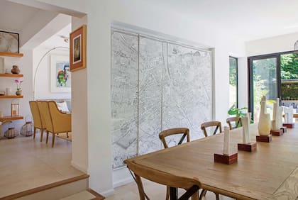 Del otro lado del living y dos escalones más abajo, el comedor tiene sillas con esterilla y mesa de madera (Landmark).