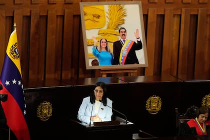 Delcy Rodriguez habla frente a un retrato de Nicolás Maduro y su mujer, Cilia Rodríguez