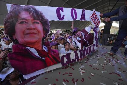 Delfina Gómez, candidata del partido Morena a la gubernatura del Estado de México, a la derecha, posa junto a una pancarta con su imagen durante un evento de campaña, el domingo 28 de mayo de 2023, en el Valle de Chalco, México. (AP Foto/Marco Ugarte)