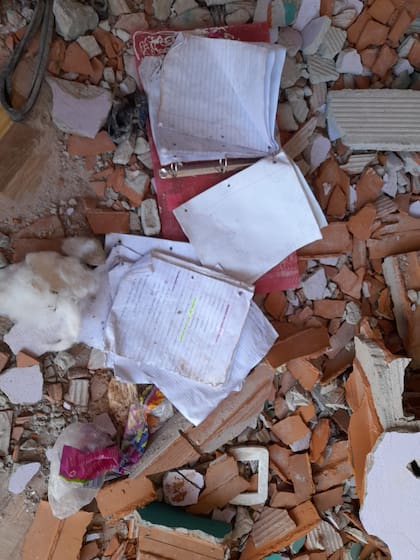 Dentro de una vivienda de dos pisos destrozada quedó, abandonada y sobre los escombros, una carpeta abierta con sus hojas y ejercicios de francés mirando a lo que fue un techo