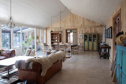 Dentro del gran ambiente social, un revestimiento en machimbre (Corralón Austral) enmarca la zona del comedor. Arañas y lámparas galponeras halladas en mercados de pulgas.