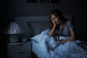 Depressed young Asian woman sitting in bed cannot sleep from insomnia