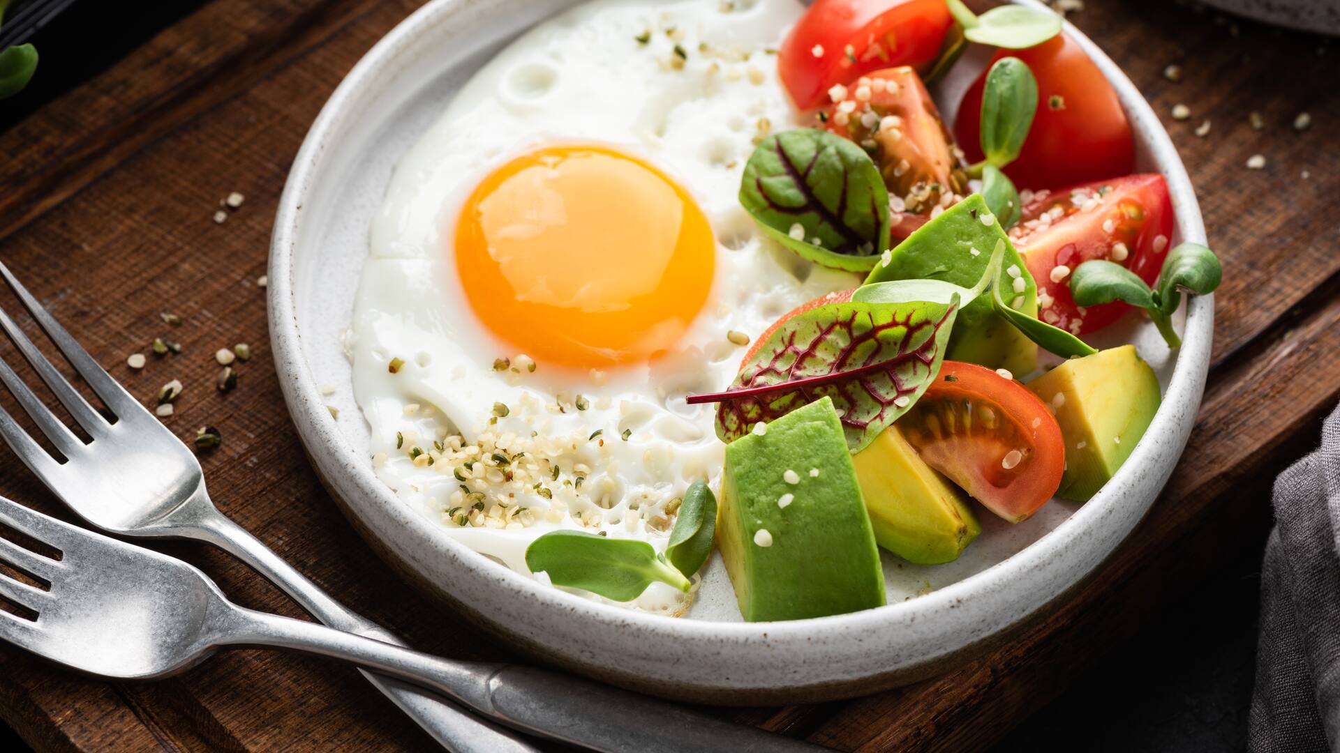 Desayuno saludable en un plato, huevo, ensalada de aguacate con tomate y semillas de cáñamo