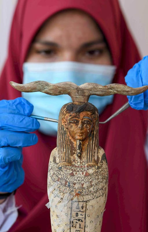 Una arqueóloga limpia una de las esculturas halladas junto alos sarcófagos