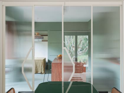Desde el comedor principal obtenemos un primer vistazo a la cocina, reservada detrás de una puerta corrediza con paneles lisos y acanalados, que permiten el paso de la luz.