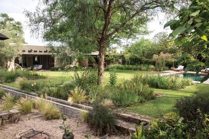 Desde la acequia hacia arriba, aparece la superficie de césped y una plantación más verde, con mayores requerimientos de agua. Del otro lado de la acequia, el xeriscape, con granza cordobesa que cubre la superficie y plantas que van semillando solas.