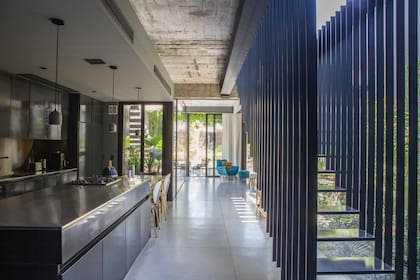 Desde la entrada, un recorrido ininterrumpido y luminoso por la cocina, el comedor diario y el living. Piso de hormigón pulido hecho en obra (Atelier M)